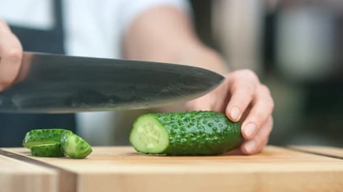 Hands of Woman Chef Cutting Fresh Ripe Green Cucumber