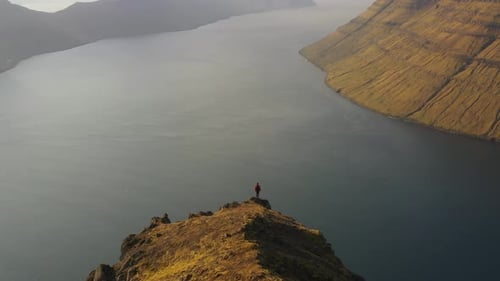 Drone Of Man Standing Over Sea And Dramatic Mountain Landscape