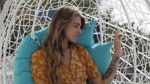 Woman Relaxing in a Wicker Egg Chair