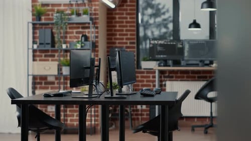 Computer Screens on Desk in Empty Data Room and Computers in Background Running Programming Code