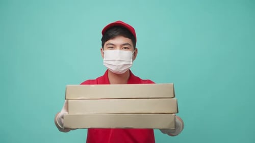 Isolated background, Delivery man wear face mask in red uniform hold pizza box and giving in ahead.