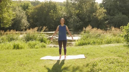 Stretching in park in the morning. Yoga exercises. Woman practicing yoga outdoors.