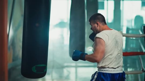Man Punches Black Boxing Bag at Gym