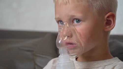 Boy doing inhalation while sitting on the couch