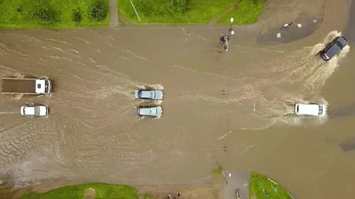 Aerial view of traffic cars driving on flooded road with rain water.