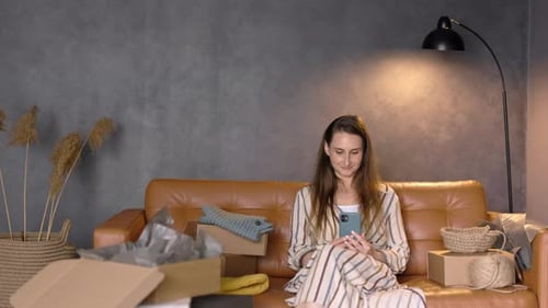 Woman Using Phone on Couch with Shipping Boxes