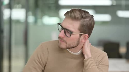 Young Adult Rubbing Neck in Office with Discomfort