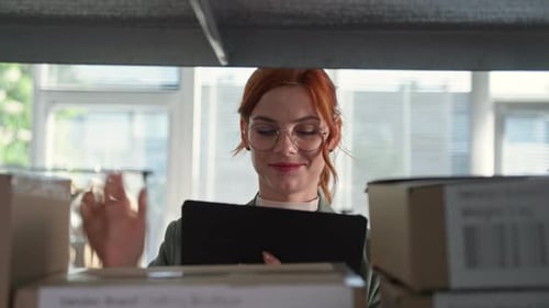 Trabalho de uma loja online: uma jovem empresária com um tablet nas mãos está verificando pedidos de