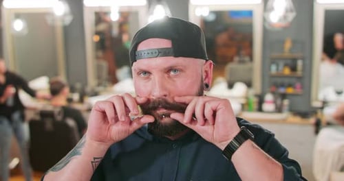Young Bearded and Mustashed Man with Tattoed Hands with Chin Ring and Tunnel Earrings in Baseball