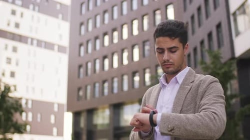 Young Adult Checks Watch Outside Office Building
