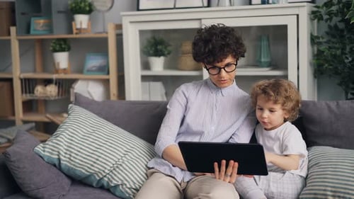 Woman and Child Using Tablet Together on Sofa