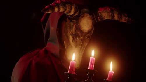 Hooded Figure with horned mask lit by candles