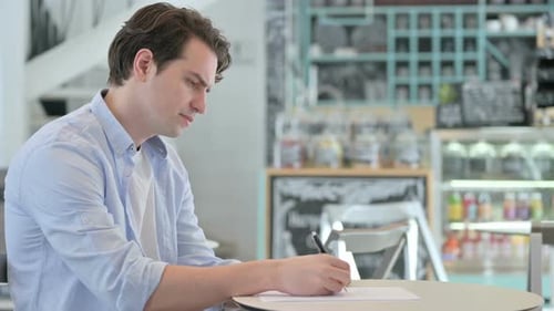 Man Working at Cafe Writing on Paper