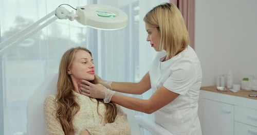 косметолог осматривает кожу лица клиентки