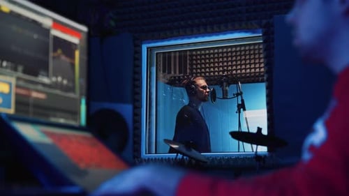 Male Rap Singer with Headphones and Sound Engineer Are Recording a New Song