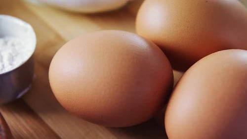 Various ingredients and brown eggs on wooden table 4k