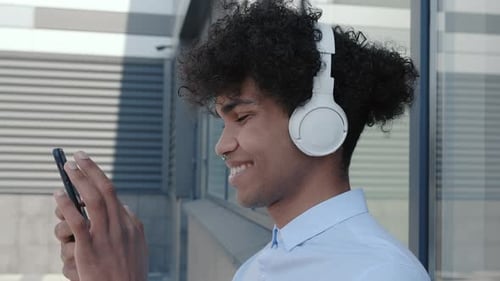 Young Man Using Smartphone with Headphones Outdoors
