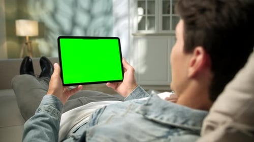 View From the Shoulder of Man Using Hand Gestures on Green Mock-up Screen Digital Tablet Computer in