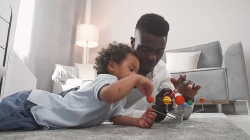 Dad and Son Play with Solar System Model