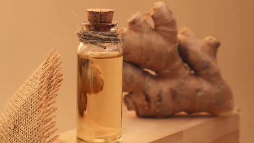 Glass Bottle of Essential Ginger Oil Ginger Root on Beige Background