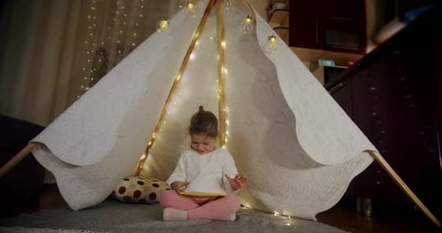 Girl Using Tablet in Lit Tent at Home