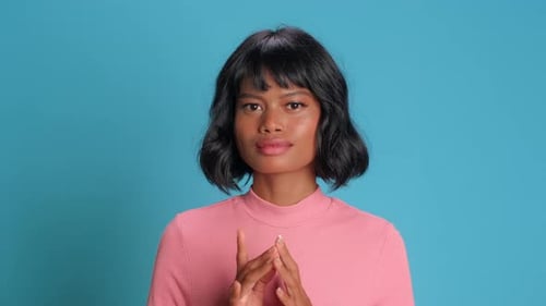Une mystérieuse femme sournoise frôle les doigts et complote quelque chose essaie par-dessus un mur bleu