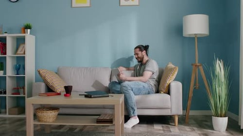 Man Using Tablet on Couch in Living Room