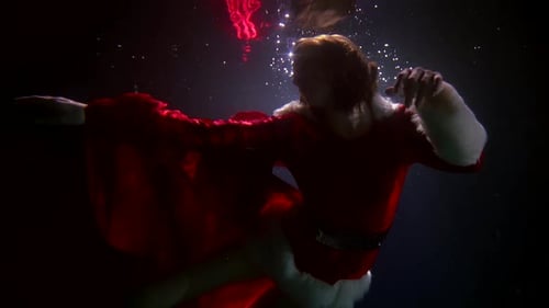 Woman Wearing a Santa Costume Swimming Underwater