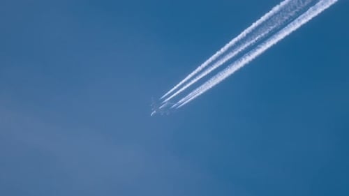 Airplane Flying High Leaving Contrails in Blue Sky