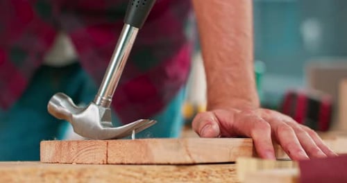 Man Hammering Nail into Wood Close Up