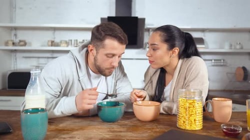 Couple Eating Breakfast Cereal Together at Kitchen Table
