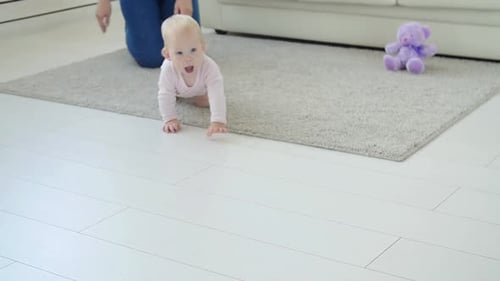 Smiling Infant Crawls on Floor Towards Camera
