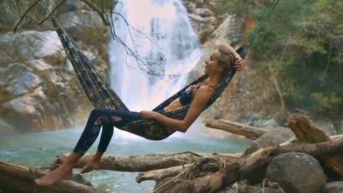 Woman Relaxing in Hammock Near Waterfall