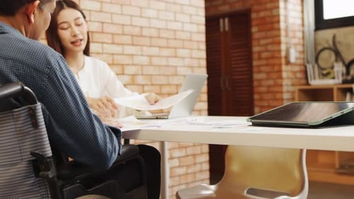 Man in Wheelchair Meeting at Workplace with Laptop