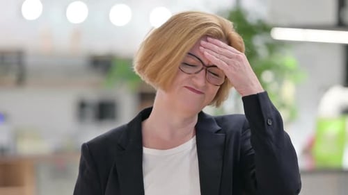 Stressed Woman Rubbing Forehead in Office