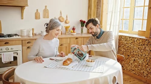 Woman and Man Sharing Coffee at Kitchen Table