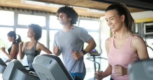 Group of Young People Running on Treadmills in Sport Gym