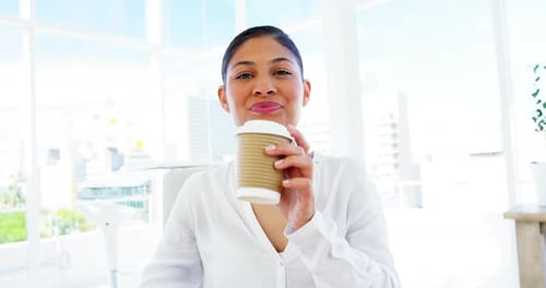 smiling woman sipping coffee in office