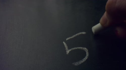 Woman Hand Holding Piece of Chalk. Unknown Female Person Writing on Blackboard