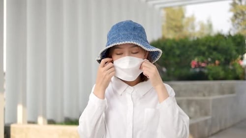 Young Woman Puts on Protective Face Mask Outdoors