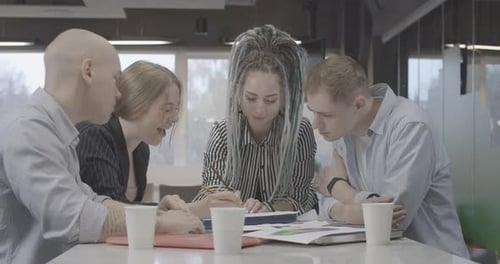 Group of Four Millennial Young People Discussing Project in Office Turning To Camera and Smiling