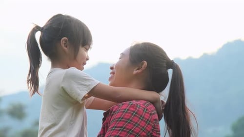 Happy little daughter hugs and kisses her mother in the park. family relationship concept