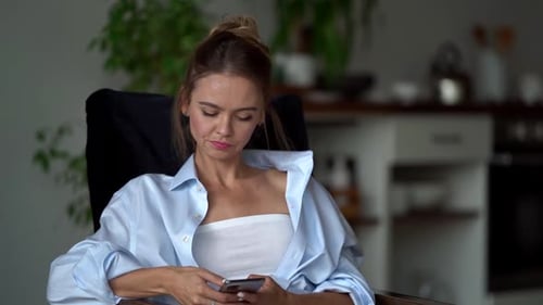 Blond Woman Using Phone While Relaxing Indoors