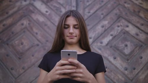 An Attractive Young Lady Using a Phone in Town. Medium Shot