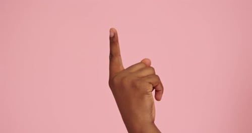 Gesto de dedo hacia arriba invertido con la mano de un hombre afroamericano aislado sobre fondo rosa