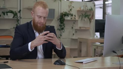 Bearded Adult Using a Smartphone in an Office