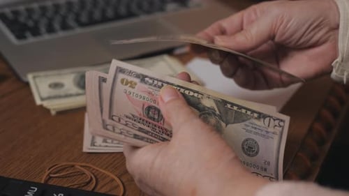Senior Adult Counting Cash on Wooden Table