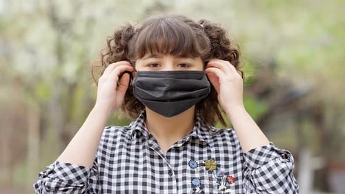 Young Girl Puts on a Protective Face Mask