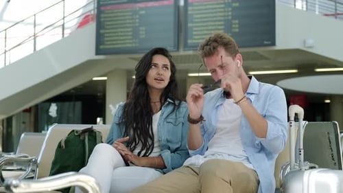 Couple Talking at Airport Gate Next to Luggage
