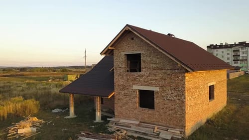 Aerial view of unfinished house with wooden roof structure covered with metal tile sheets under